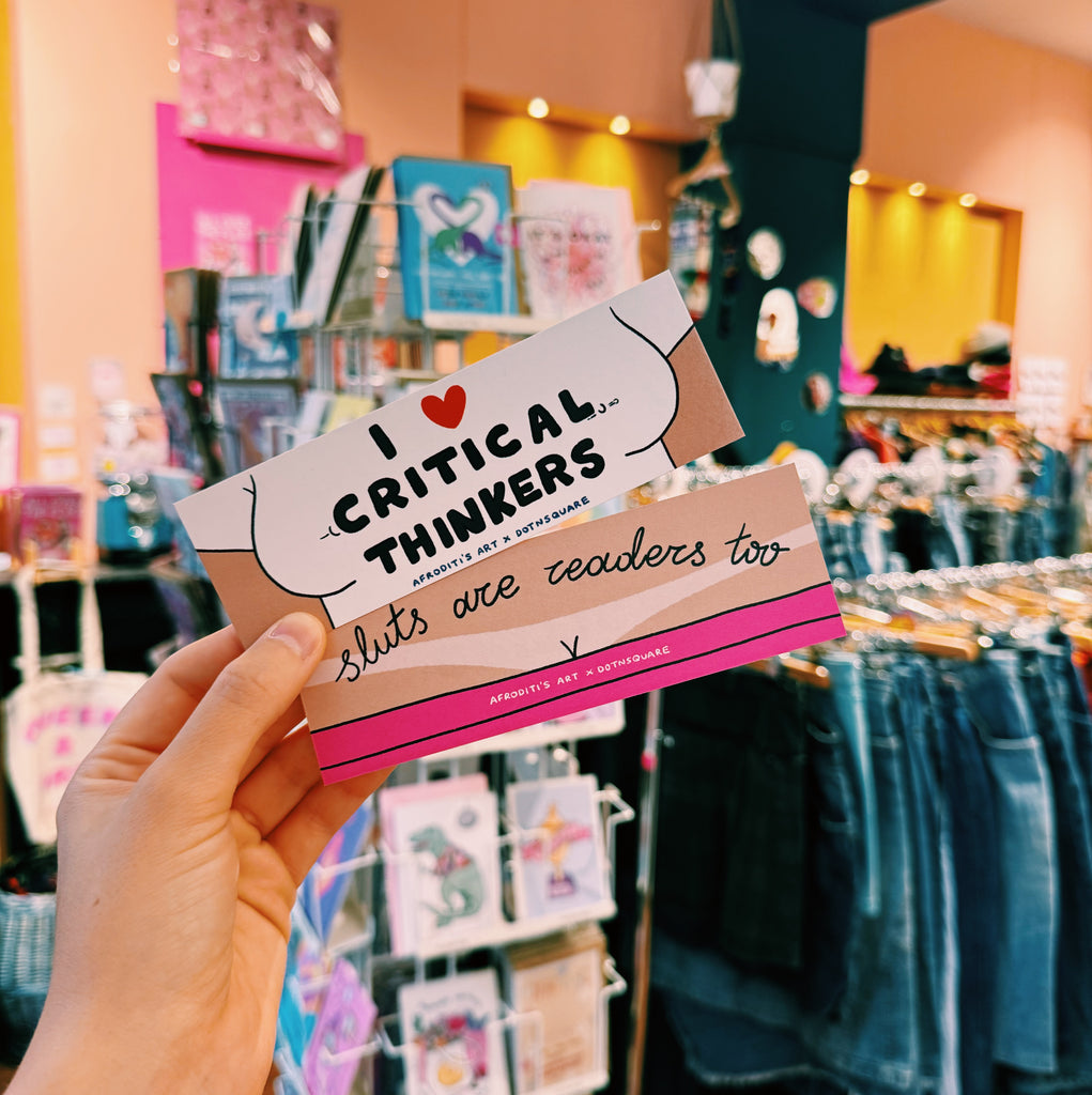 Bookmark with text 'I love critical thinkers, sluts are teachers too' held in a store setting.