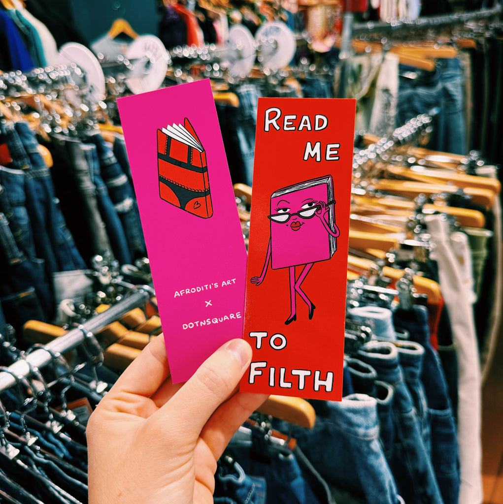Two colorful bookmarks held in front of clothing racks