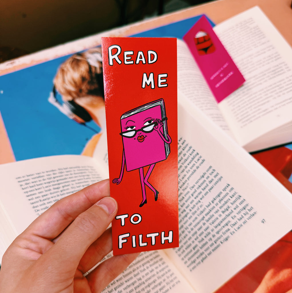 Red bookmark with cartoon character and text 'Read Me To Filth' held over an open book.